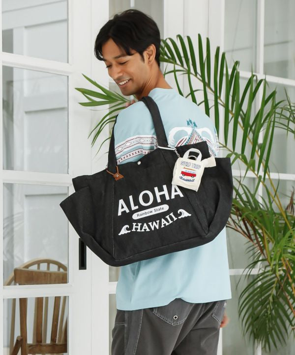 ALOHA HAWAII ロゴ入りブラックデニムトートバッグを肩掛けしたコーディネート