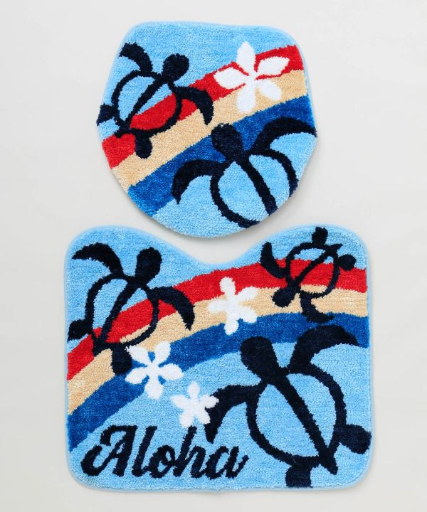 ホヌと虹が描かれたハワイアンデザインのトイレマットとフタカバーセット。立体的な刺しゅうが特徴の南国インテリア。
