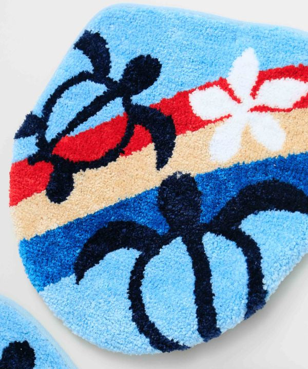 ホヌと虹が描かれたハワイアンデザインのトイレマットとフタカバーセット。立体的な刺しゅうが特徴の南国インテリア。