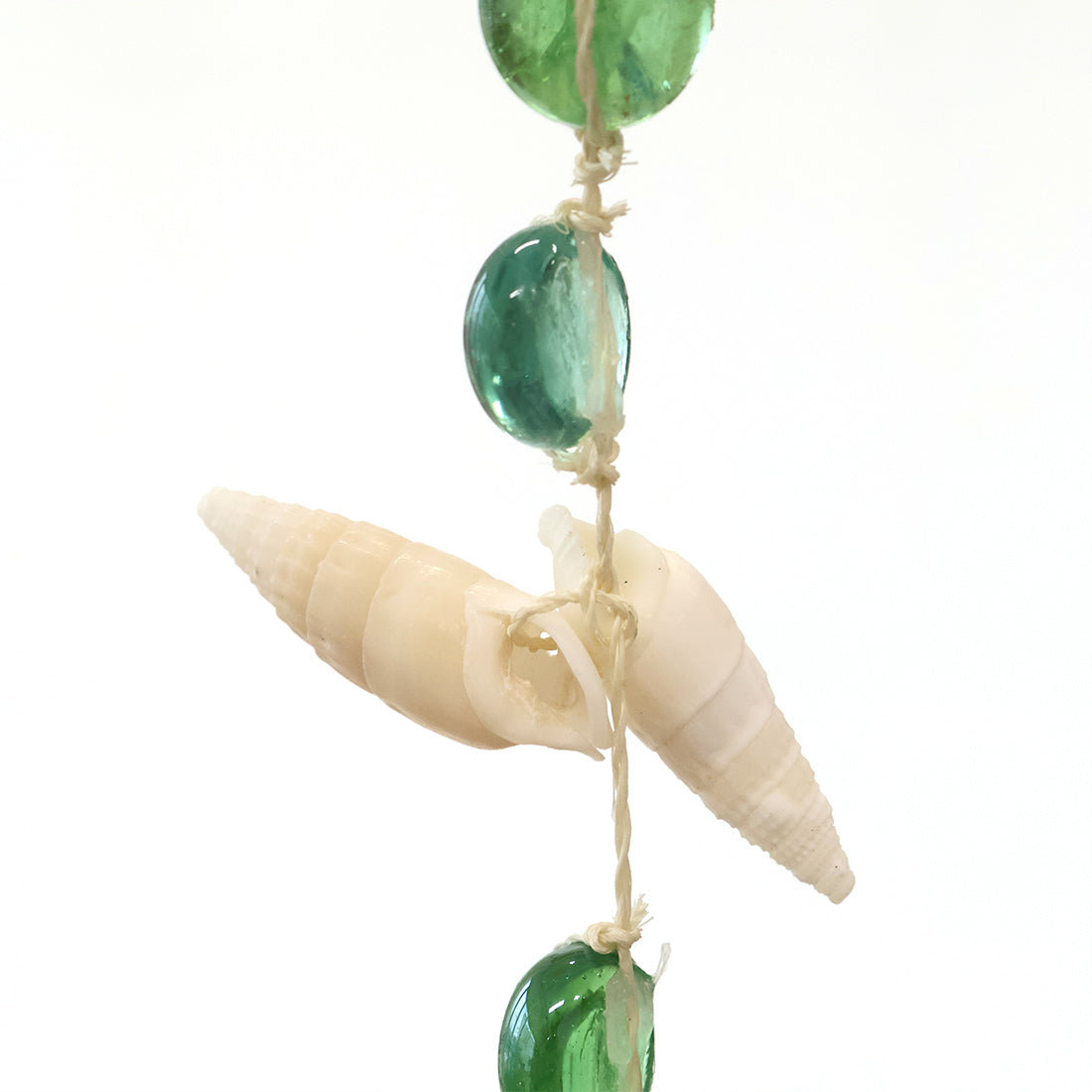 ブルーとグリーンのガラスとスターフィッシュのサンキャッチャーが窓辺で光を受けて揺れるマリンインテリア